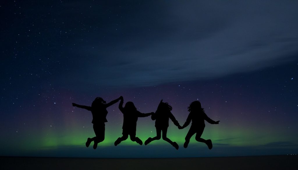 Four people jumping with Northern Nights in Lapland behind them