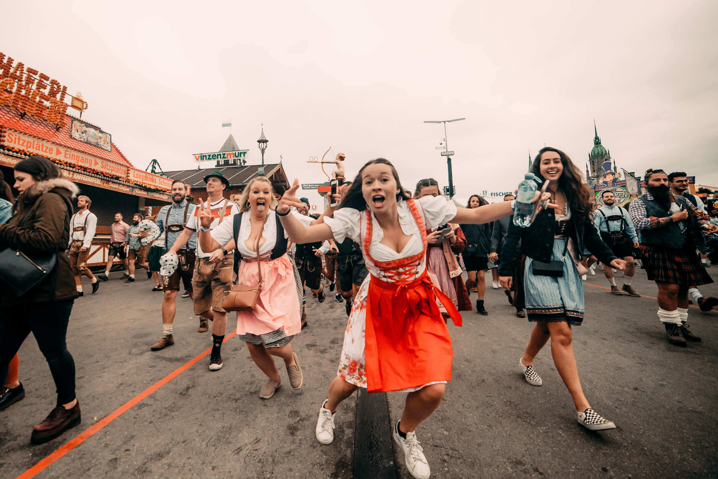 Group of friends running together at Oktoberfest festival grounds
