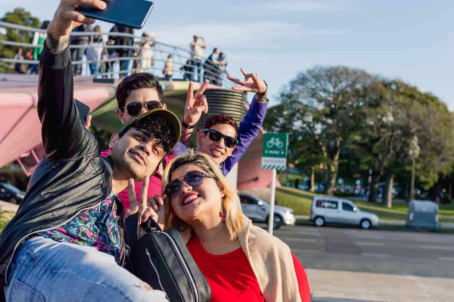 Young adults giving peace signs posing for selfie near bus terminal