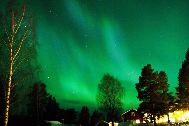 Vivid green aurora borealis stretching across the night sky in Alaska’s wilderness