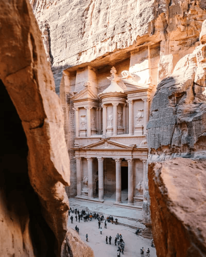 View of Petra’s Treasury through the Siq canyon, with visitors gathered at the UNESCO World Wonder Yes-Trips Jordan Tour