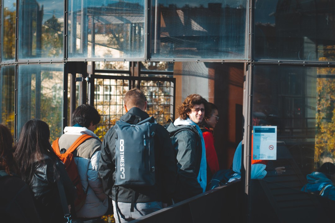 People in line outside a glass building entrance.