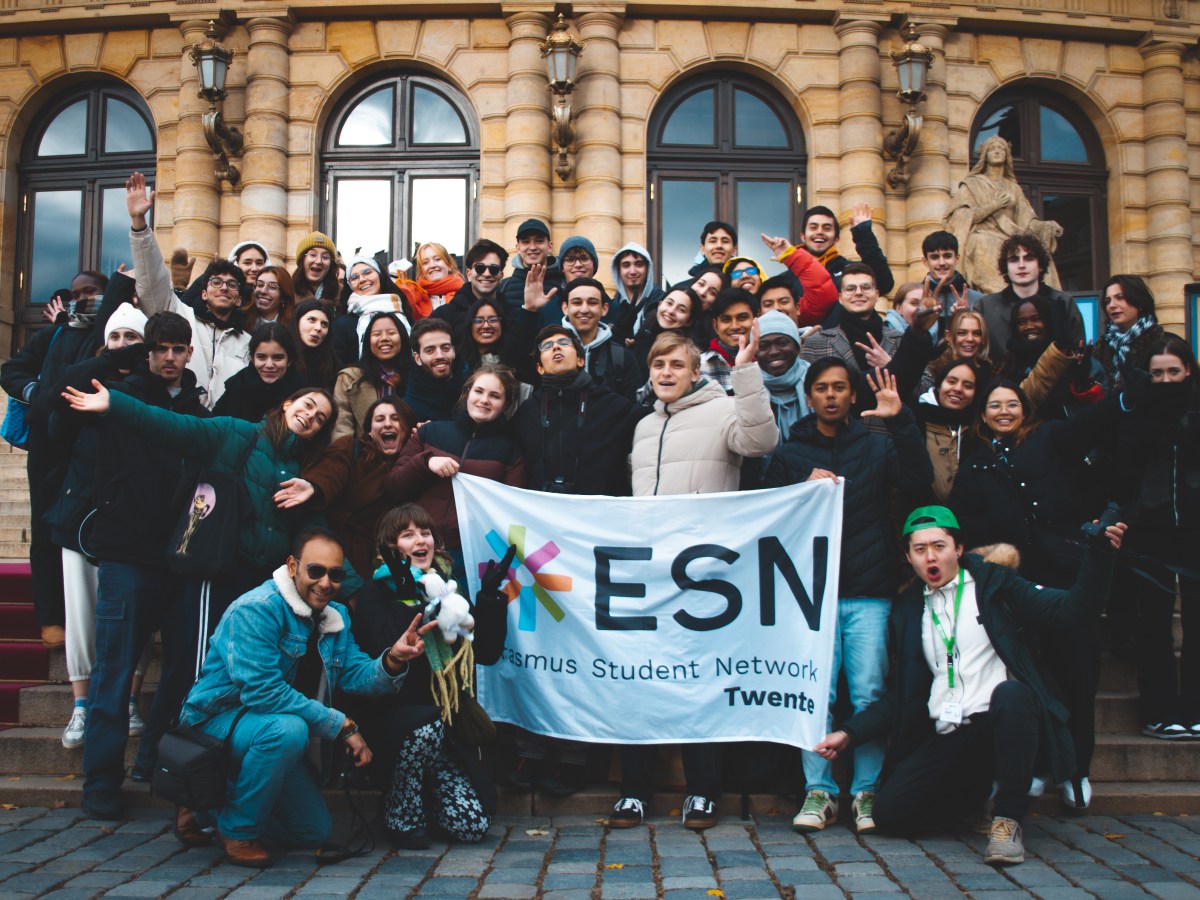 Group of students holding an ESN Twente banner in front of a building.