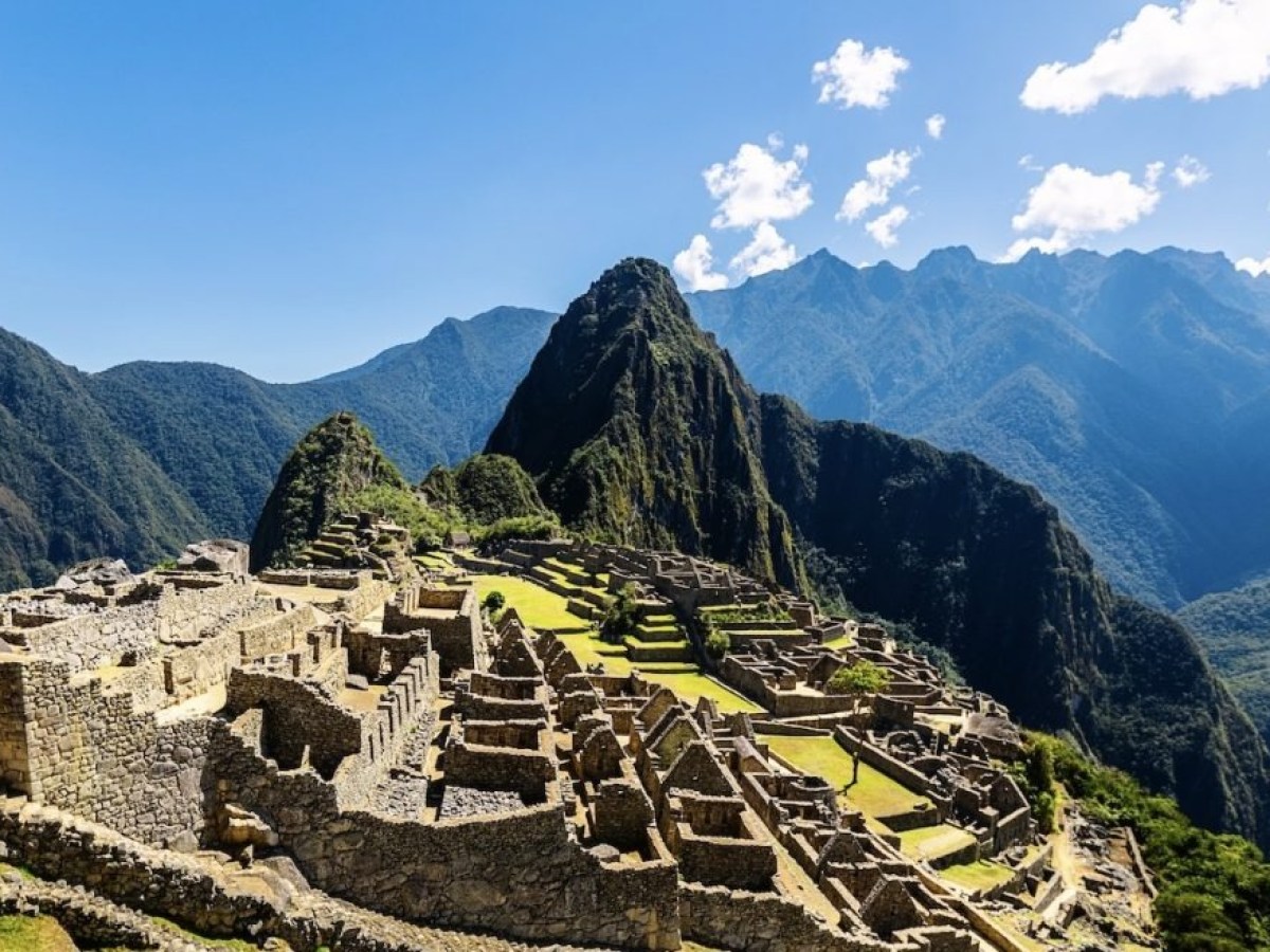 Machu Picchu ruins with mountain backdrop under a clear blue sky.