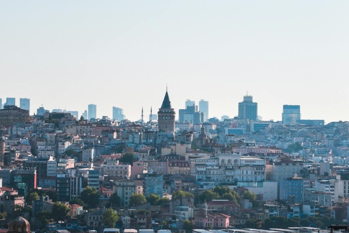 City skyline with waterway, distant buildings, and tower under clear blue sky.