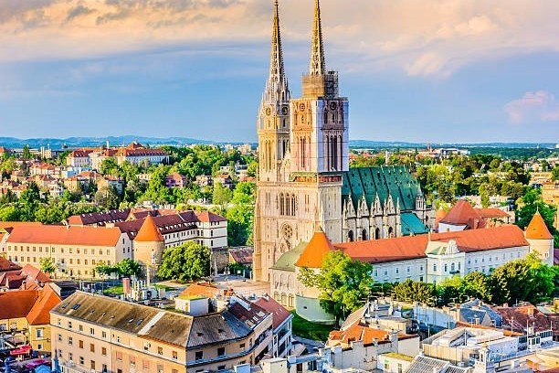 Historic cathedral with twin spires in a European cityscape at sunset.