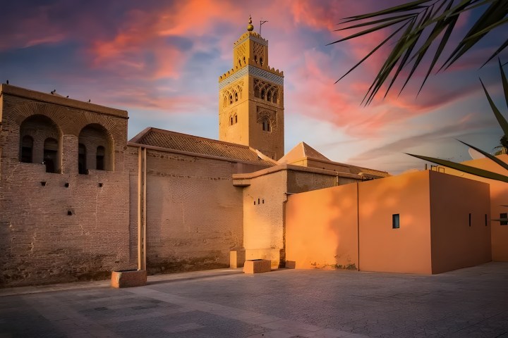 Sunset view of a mosque tower with colorful sky in the background.