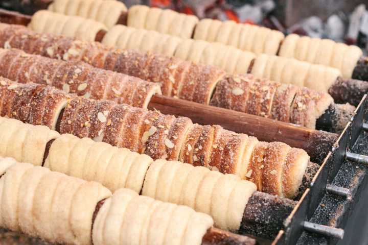 Rows of traditional chimney cakes baking over an open flame.