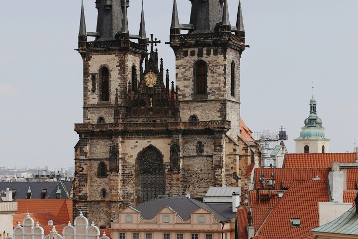 Gothic church with twin spires overlooks a square with colorful historic buildings.