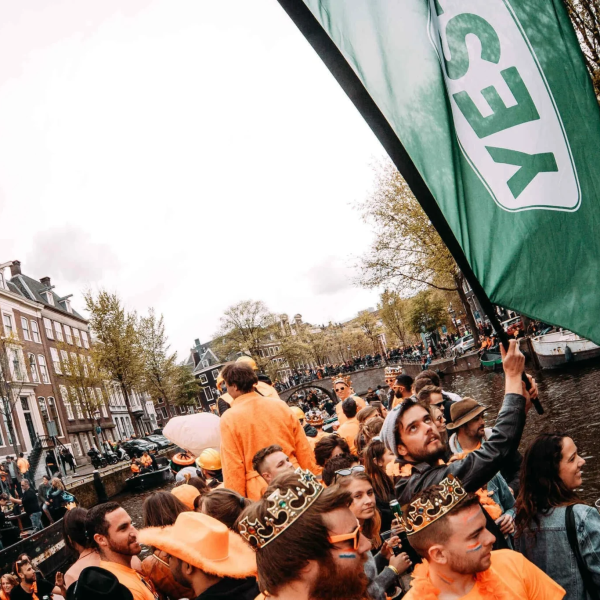 Crowd in orange on a canal boat with a 'YES' flag.