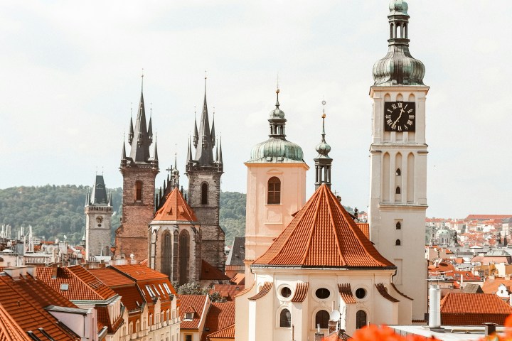 View of Prague skyline with red-roofed buildings and church towers.