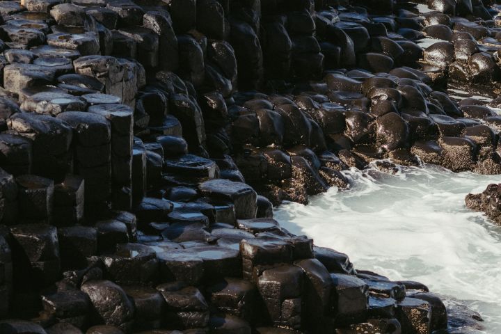 Rough ocean waves against basalt rock columns.