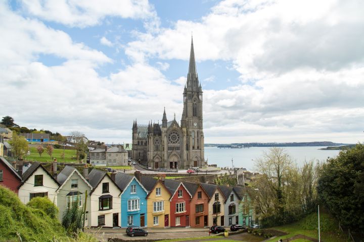 Colorful houses and a large church overlooking a bay under a cloudy sky.