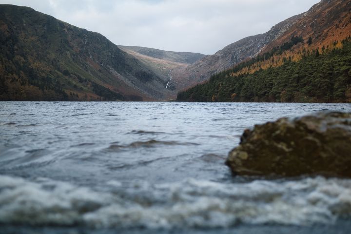 Lake view with distant waterfall and hills under a cloudy sky.
