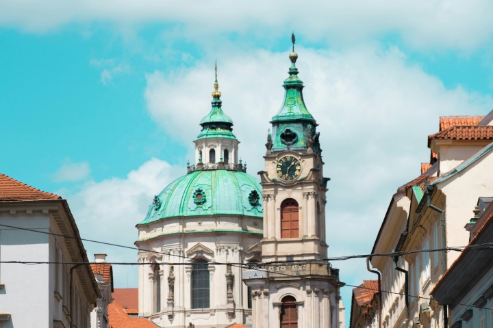 Historic city street with church domes and blue sky.