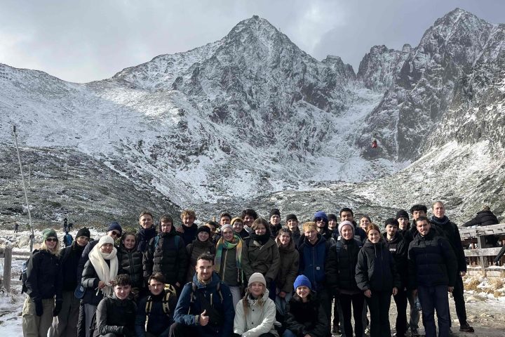 Large group of people posing on a snowy mountain landscape.
