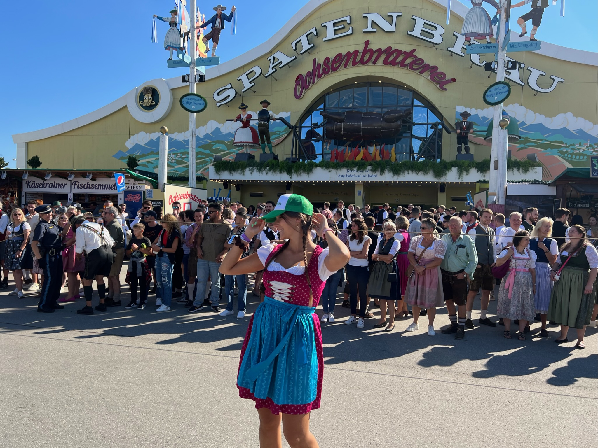 Person in traditional attire outside a crowded festival tent with Spatenbräu