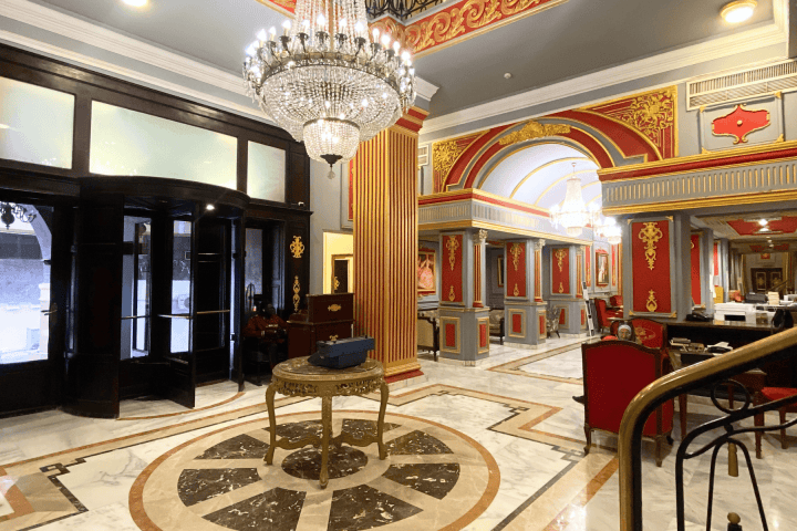 Luxurious hotel lobby with ornate decor, chandeliers, and a revolving door.