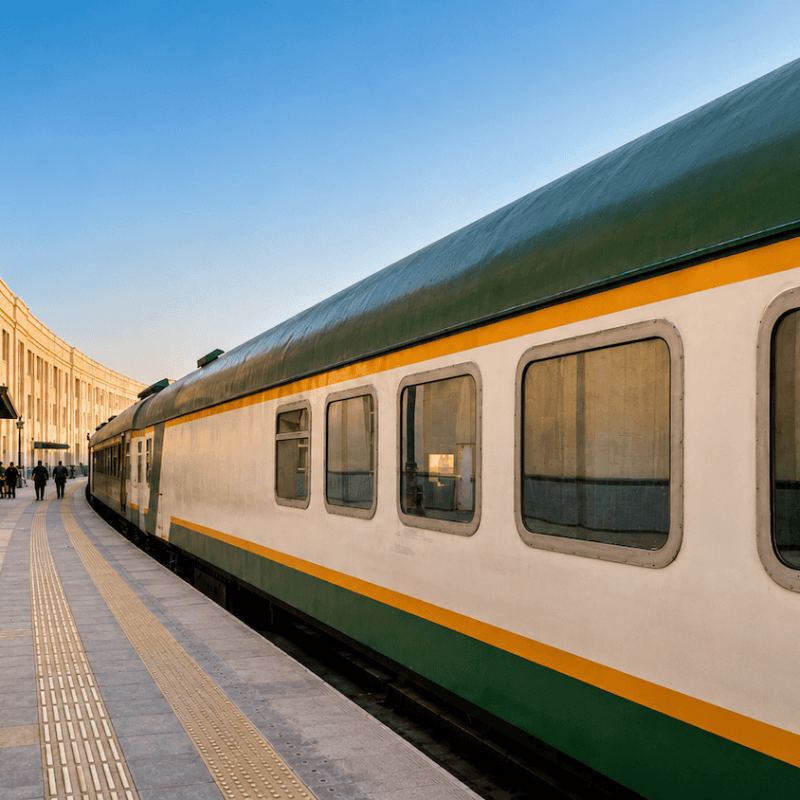 Vintage train parked by an elegant station with arched windows.