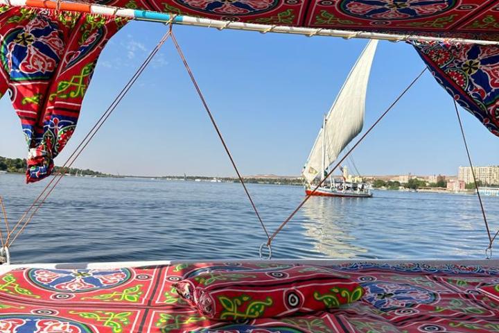 Sailboat on a river viewed from inside a colorful fabric-draped boat.