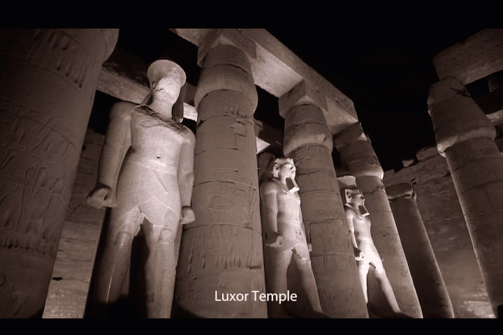 Statues and columns at Luxor Temple, illuminated at night.