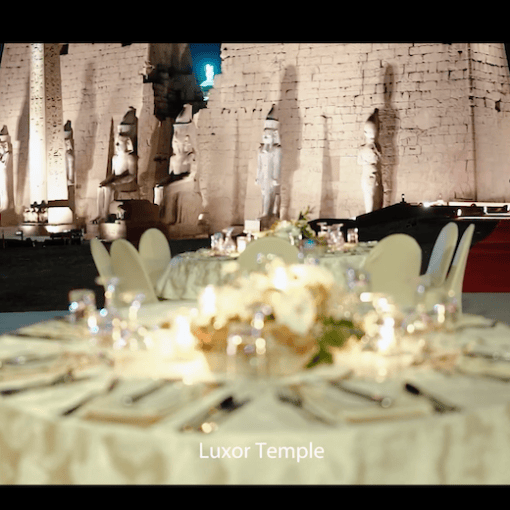 Elegant tables set in front of illuminated ancient ruins at Luxor Temple.