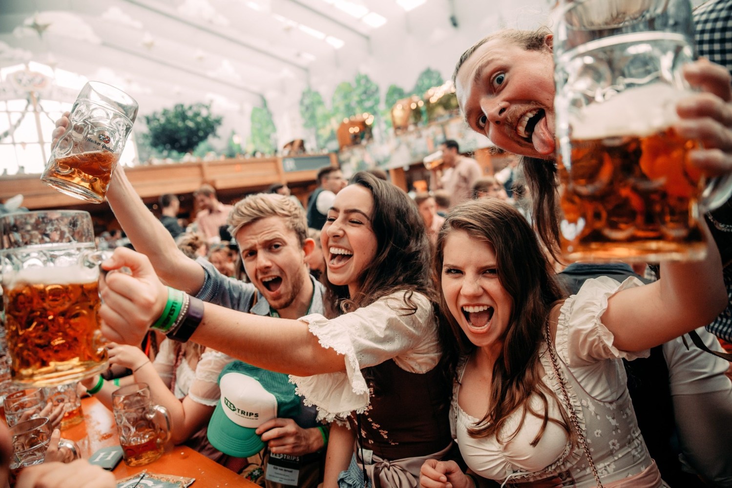 Group of joyful people holding beer mugs at a festively decorated event.